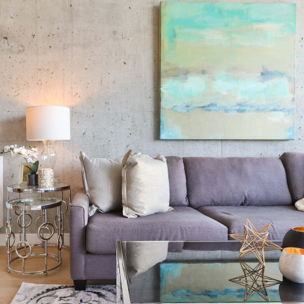 a lounging area housing a large grey sofa, decorated with a lamp and painting